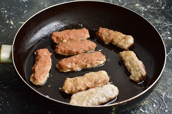 Fried meat sausages in a pan - juicy and fragrant