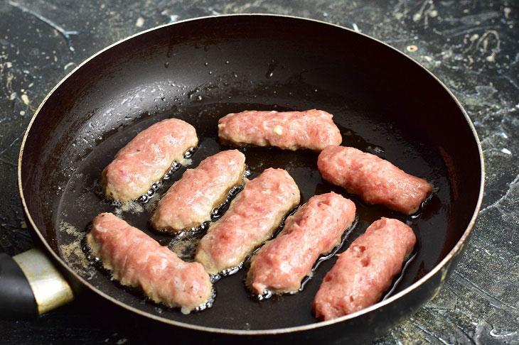 Fried meat sausages in a pan - juicy and fragrant