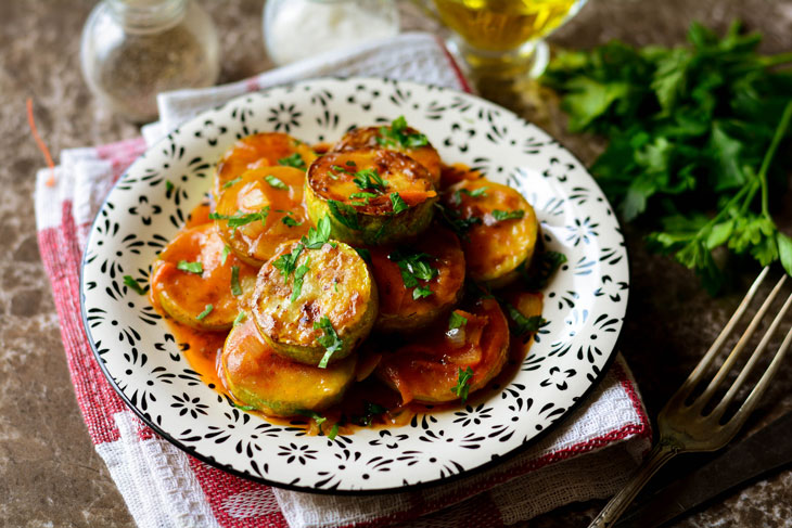 Zucchini stewed in tomato sauce in a pan - unusual and bright in taste